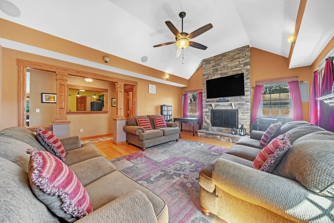 Market-ready living room with a vaulted ceiling, stone fireplace and furnished seating area.