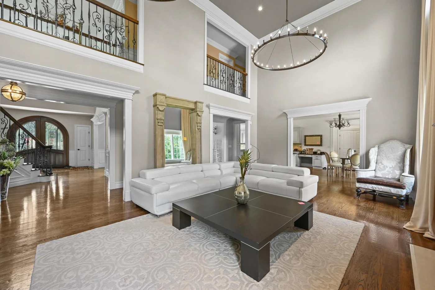 High-end living room with a two-story ceiling, large chandelier and staged furnishings.