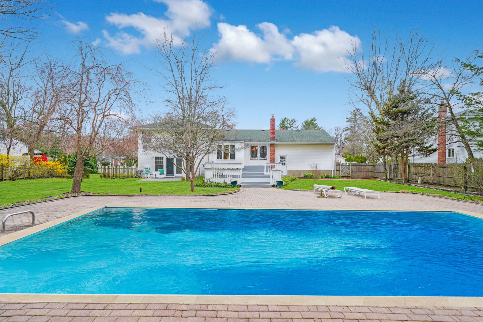 A Smithtown, New York home with an in-ground pool and backyard patio