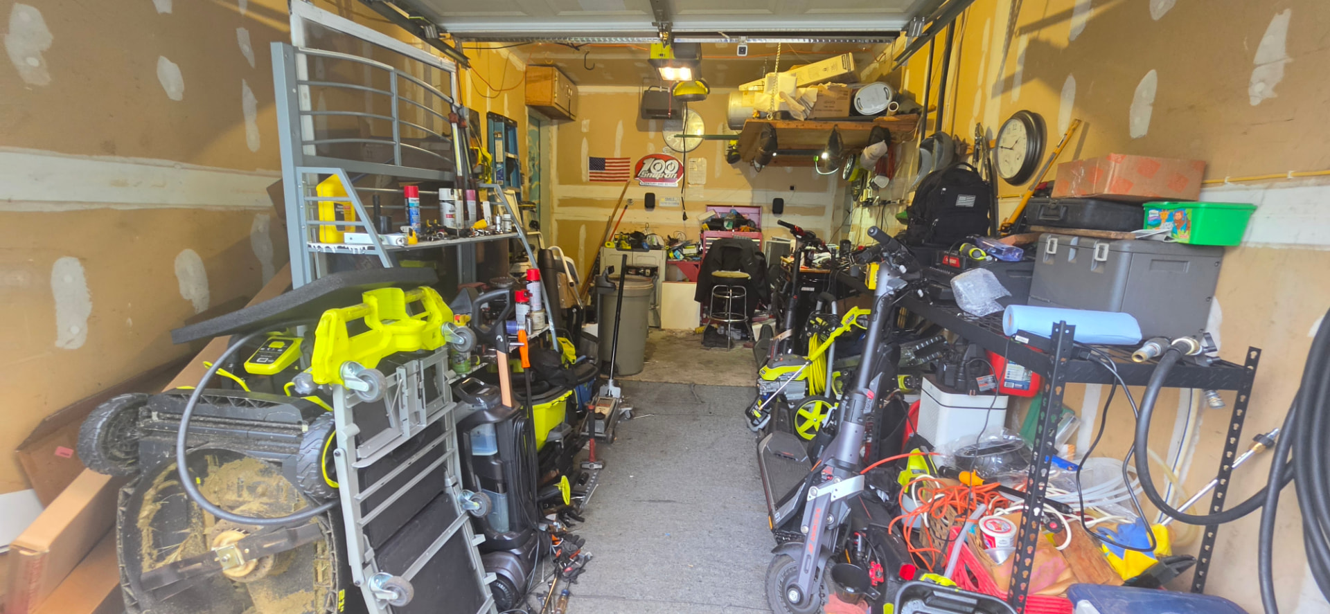 Garage of the Central Islip property packed floor to ceiling with tools, scooters, shelving and stored belongings