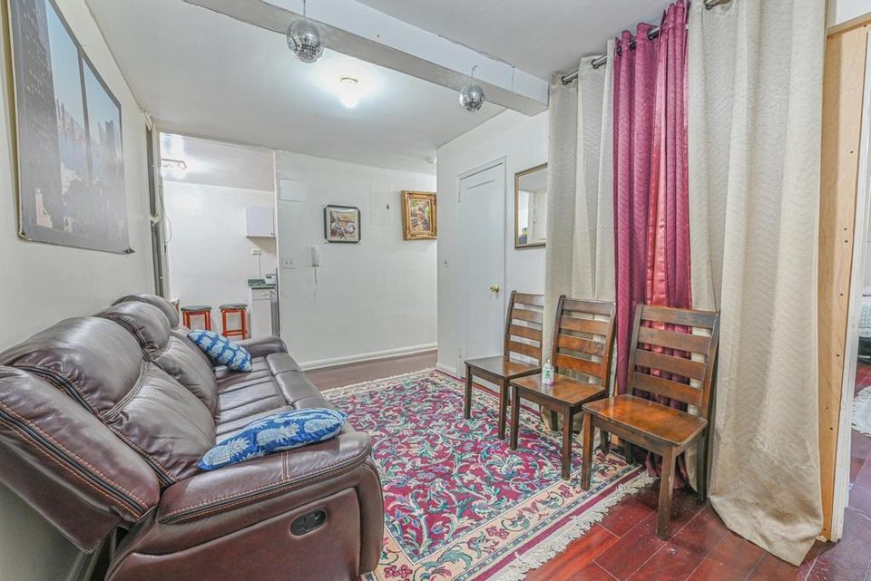 Curtain covering a makeshift plywood partition in a Jackson Heights co-op living room before renovation