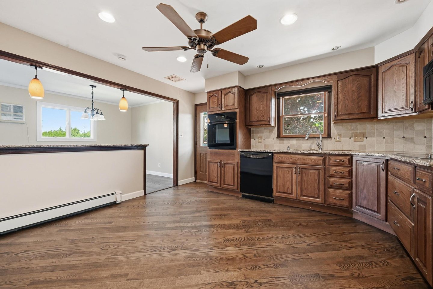 The same kitchen after the work, emptied with refinished hardwood floors, neutral walls and updated counters