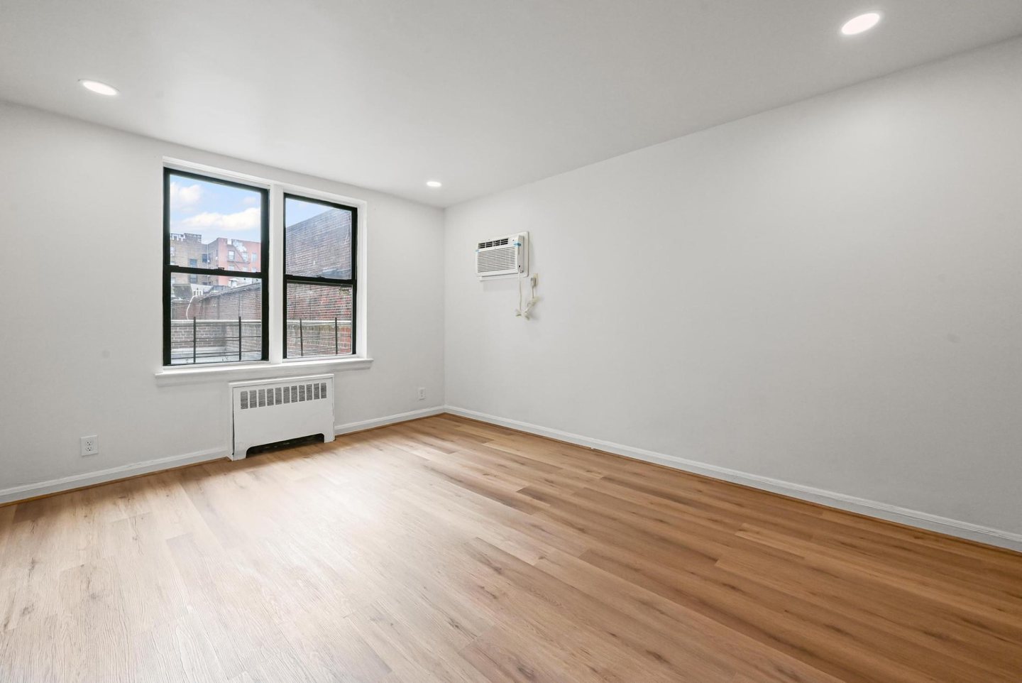 Renovated Jackson Heights co-op bedroom with new flooring, paint and overhead lighting.